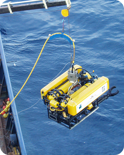 A yellow remotely operated vehicle (ROV) being lowered into the ocean for a rescue mission.
